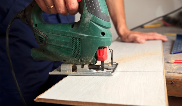 L'uomo sta tagliando il laminato con il puzzle