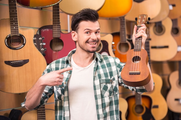 L'uomo sta tenendo le ukelele nel negozio di musica.