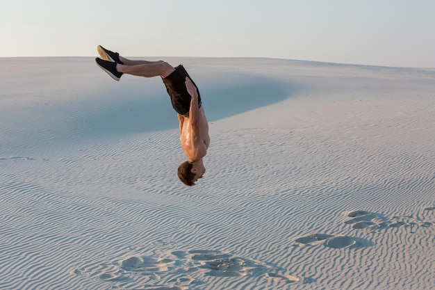 L'uomo studia il parkour da solo. Acrobazie sulla sabbia