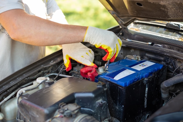 L'uomo svita i bulloni di montaggio della batteria con una chiave inglese, installando e sostituendo i pezzi di ricambio su un'auto.