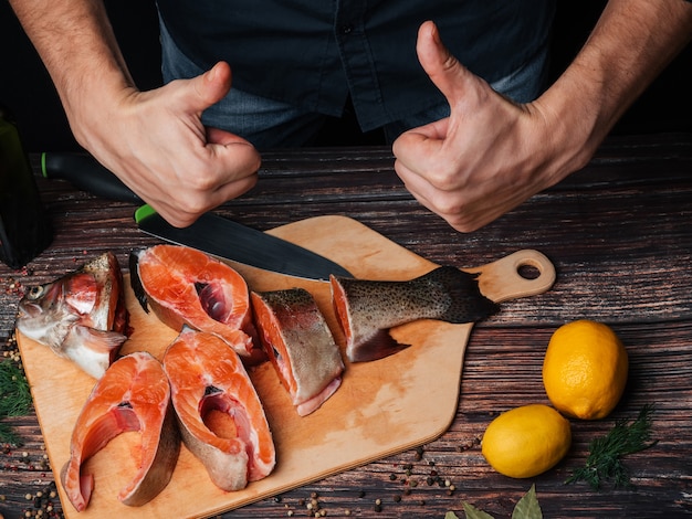 L'uomo taglia la trota cruda fresca a pezzi per cucinare