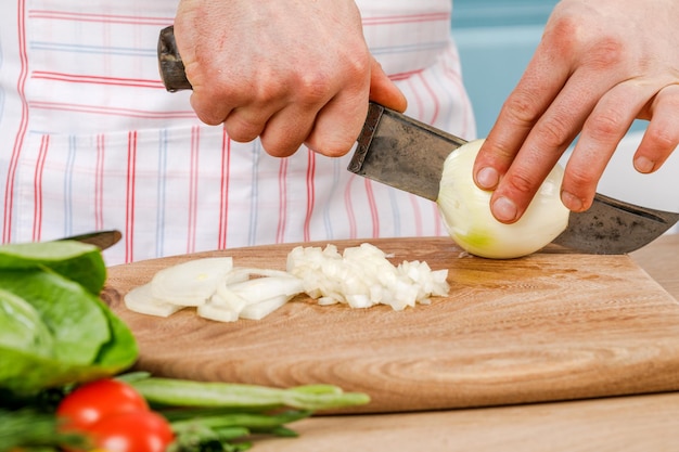 L'uomo taglia una cipolla bianca con un coltello Il concetto di cucina