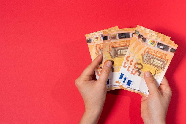 L'uomo tiene i soldi e conta le banconote da 50 euro su uno sfondo rosso Banner per prestiti e prestiti di denaro con spazio per il testo