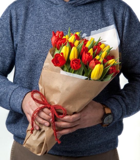 L'uomo tiene il bouquet di tulipani gialli e rossi relativi al nastro di San Valentino