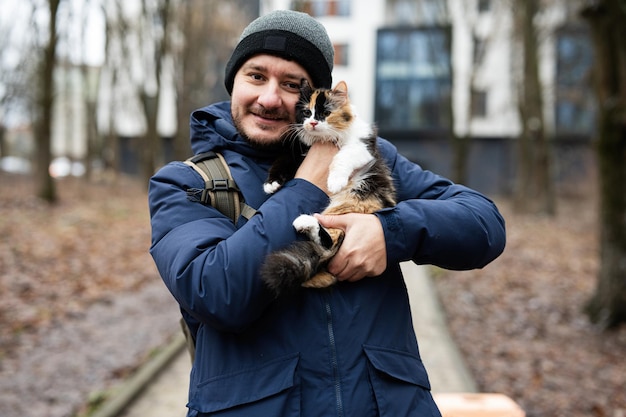 L'uomo tiene il gattino nelle mani all'aperto al parco