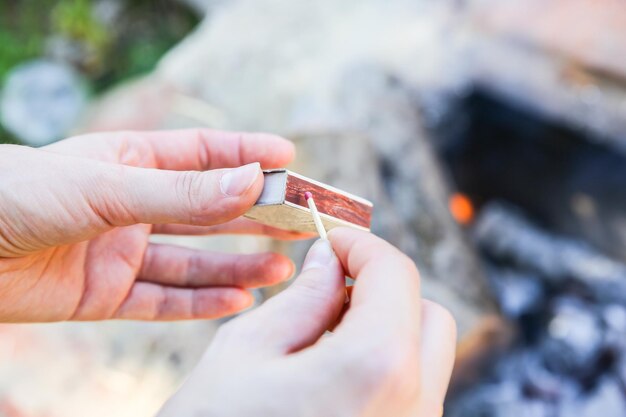 L'uomo tiene in mano i fiammiferi La persona sta facendo fuoco all'aperto