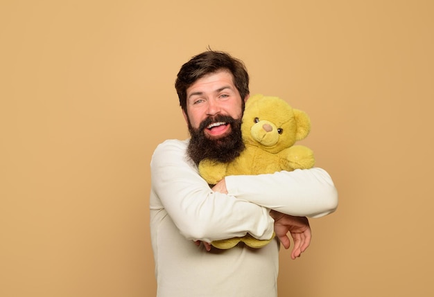 L'uomo tiene l'orsacchiotto di peluche, l'uomo sorridente abbraccia l'orsacchiotto per le feste di compleanno o