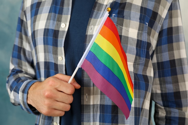 L'uomo tiene la bandiera LGBT contro il blu