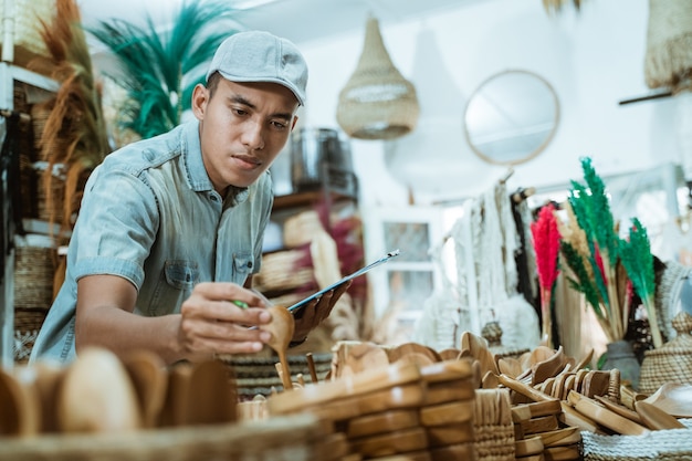 L'uomo tiene un oggetto artigianale e appunti mentre controlla gli oggetti tra gli oggetti artigianali nella galleria artigianale