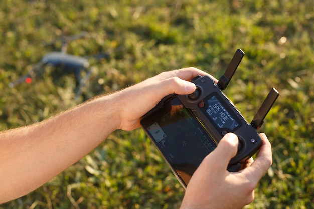 L'uomo tiene un telecomando drone nelle sue mani il quadricottero è a terra pronto per andare e volare