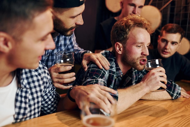 L'uomo triste si sente male Gruppo di persone insieme al chiuso nel pub si divertono durante il fine settimana