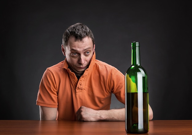 L'uomo ubriaco guarda la bottiglia di vino