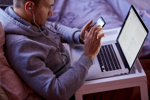 L'uomo usa il suo laptop e telefono per lavoro e affari a casa Studiare freelance shopping online concetto di webinar di lavoro a distanza Lavora con i clienti da casa Copia spazio di chromakey Alta qualità