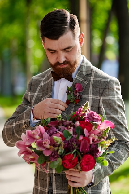 L'uomo vestito elegante vestito che tiene il mazzo di fiori