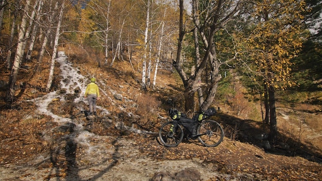 L'uomo viaggia su terreno misto cicloturismo con bikepacking. Il viaggio del viaggiatore con le borse della bicicletta. Bikepacking da turismo sportivo.