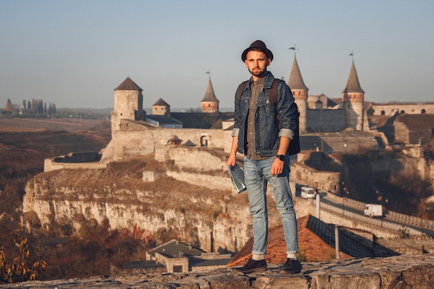 L'uomo viaggiatore con una mappa in mano si trova sullo sfondo del vecchio castello