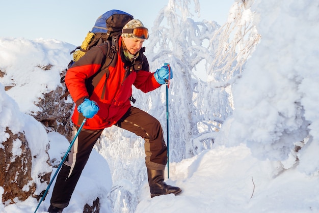 L'uomo zaino in spalla nelle montagne invernali supera la fessura tra le rocce coperte di neve