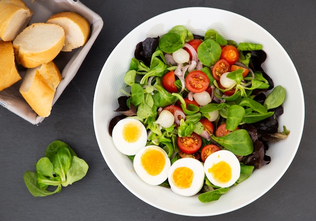 L'uovo di insalata mescolato con pomodori dolci, aglio sottaceto, cipolle e spinaci sono una dieta sana per ogni pasto.