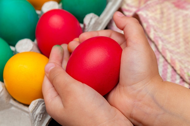 L'uovo di Pasqua rosso in mani dei bambini si chiude su