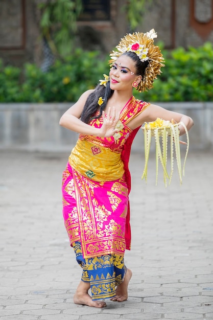 La ballerina balinese balla con una ciotola di petali di fiori