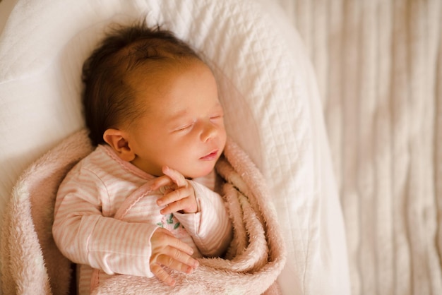 La bambina addormentata indossa il pigiama sdraiato nella culla avvolta in una coperta da vicino Infanzia