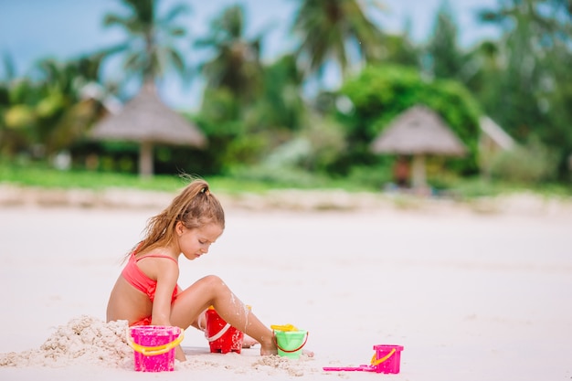 La bambina adorabile che gioca con la spiaggia gioca durante la vacanza tropicale