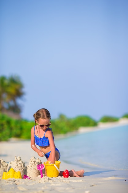 La bambina adorabile che gioca con la spiaggia gioca durante la vacanza tropicale