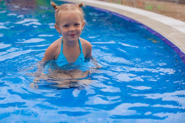 La bambina adorabile gode nella piscina