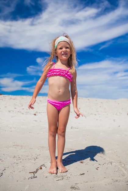 La bambina adorabile in bello costume da bagno si diverte alla spiaggia tropicale