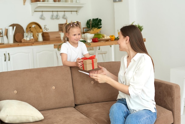 La bambina adorabile regala a sua madre una carta e un regalo per l'8 marzo o la festa della mamma Concetto di famiglia amorevole