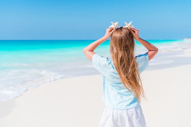 La bambina adorabile si diverte alla spiaggia tropicale durante la vacanza