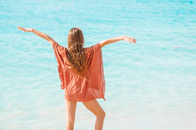 La bambina adorabile si diverte alla spiaggia tropicale durante la vacanza