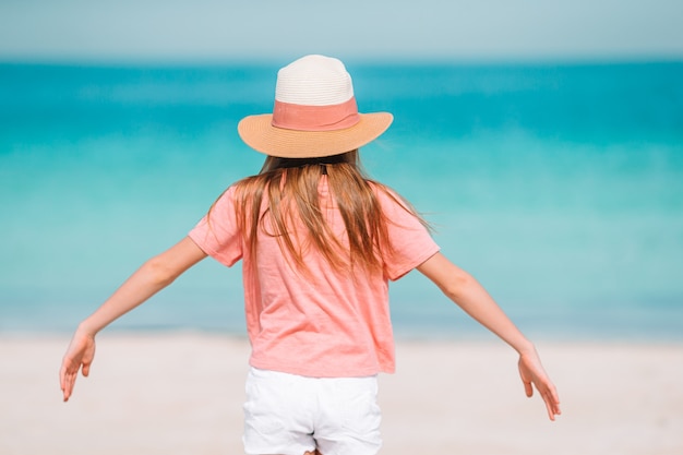 La bambina adorabile si diverte alla spiaggia tropicale durante la vacanza