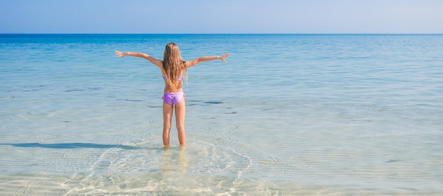 La bambina adorabile si diverte alla spiaggia tropicale durante la vacanza