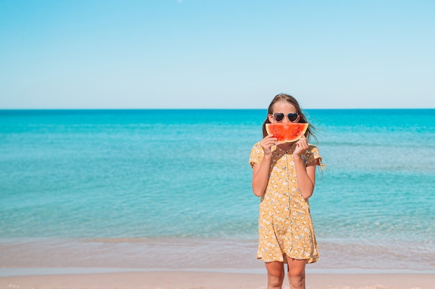 La bambina adorabile si diverte alla spiaggia tropicale durante le vacanze
