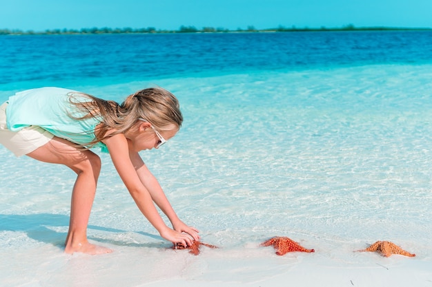 La bambina adorabile si diverte alla spiaggia tropicale durante le vacanze