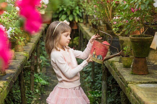 La bambina aiuta ad innaffiare le piante e il giardinaggio in serra Concetto di agricoltura familiare di negozio di fiori di giardino botanico