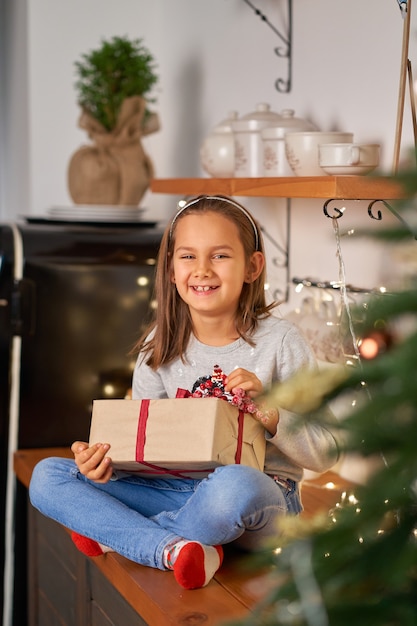 La bambina apre una scatola con un regalo di Natale di Babbo Natale