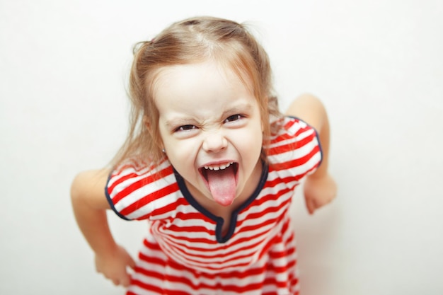 La bambina arrabbiata mostra la sua lingua in una smorfia divertente
