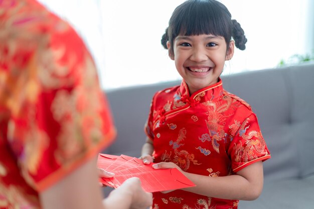 La bambina asiatica felice ha ricevuto una busta rossa dalla madre per il capodanno cinese