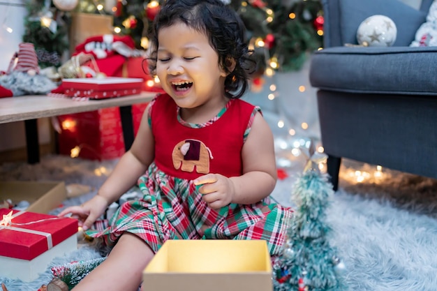 La bambina asiatica felice si diverte il giorno di Natale. Bambino con genitore con decorazione dell'albero di Natale a casa in vacanza.