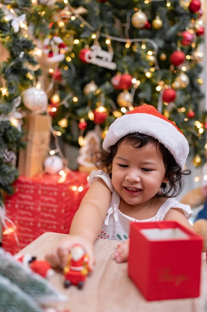 La bambina asiatica felice si diverte il giorno di Natale. Bambino con genitore con decorazione dell'albero di Natale a casa in vacanza.