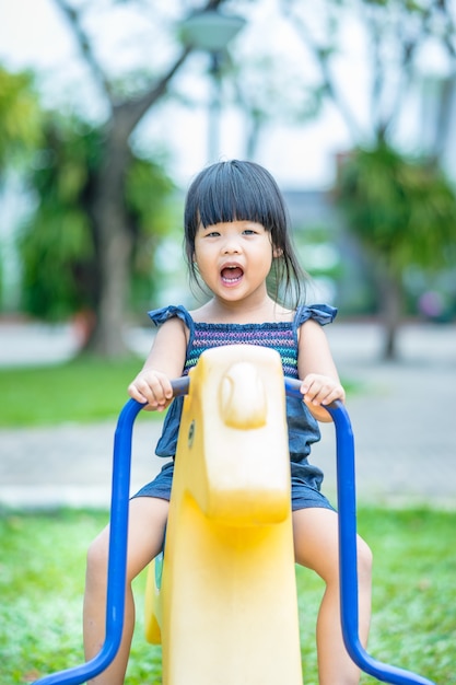 La bambina asiatica gode di di giocare in un campo da giuoco dei bambini