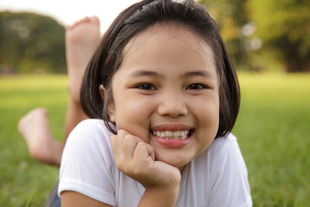 La bambina asiatica si rilassa e sorridendo felicemente nel parco