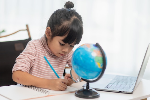 La bambina asiatica sta imparando il concetto del modello del globo di salvare il mondo e imparare attraverso l'attività di gioco per l'educazione dei bambini a casa