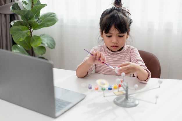 La bambina asiatica studia il sistema solare nella classe di geografia guardando il modello in scala dei pianeti