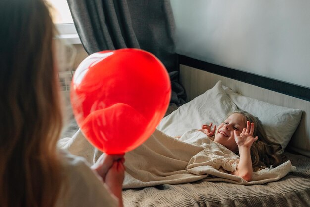 La bambina augura un buon compleanno alla sorella della sua ragazza al mattino regala un palloncino a cuore