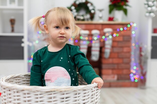 La bambina bionda gioca seduta in un cesto di vimini