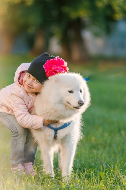 La bambina cammina con il suo cane Samoiedo nel parco in autunno