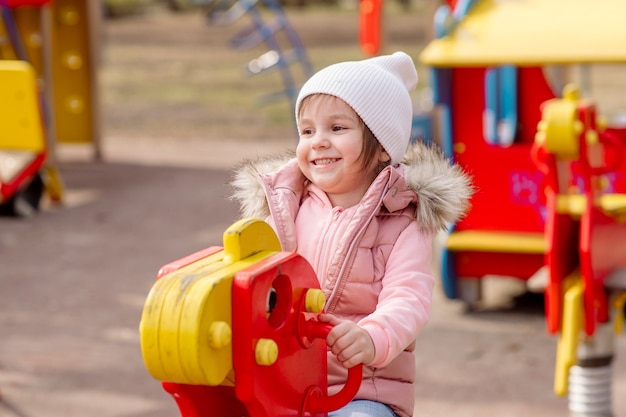 La bambina cammina nel parco giochi in strada in primavera